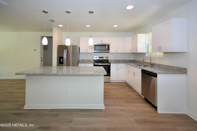 kitchen featuring a kitchen island, a sink, white cabinets, light wood-style floors, and appliances with stainless steel finishes