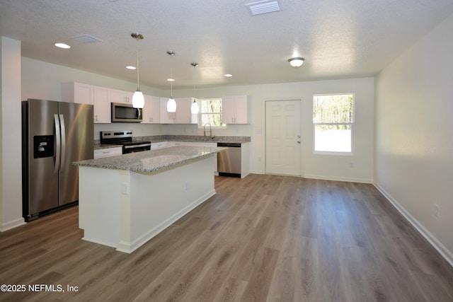 kitchen with a kitchen island, white cabinetry, stainless steel appliances, and a sink