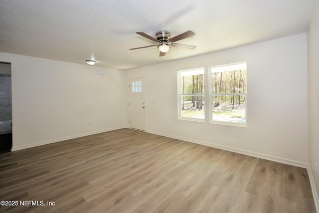 unfurnished room with baseboards, a textured ceiling, ceiling fan, and wood finished floors