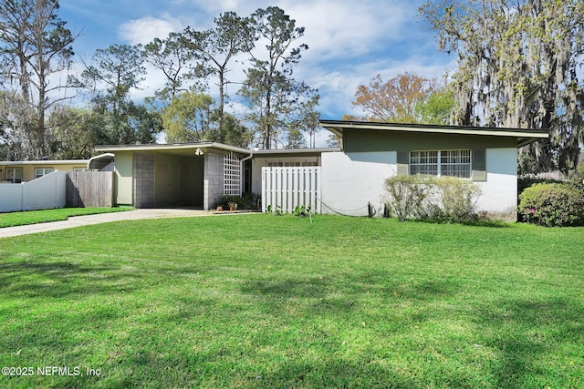 view of front of property with an attached carport, concrete driveway, fence, and a front yard