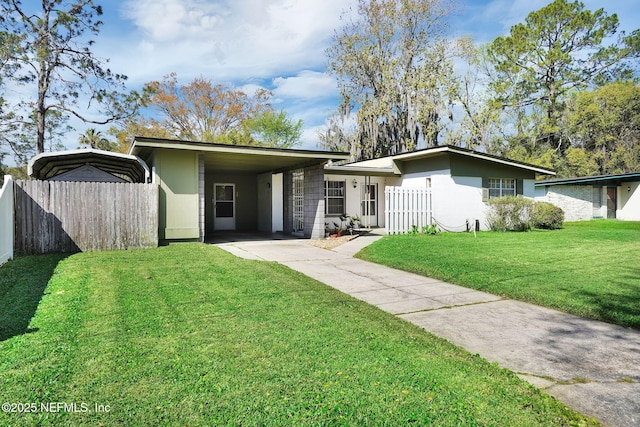 view of front of house with stucco siding, driveway, a front lawn, fence, and an attached carport