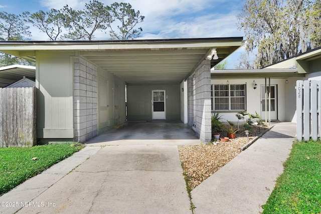 view of parking / parking lot featuring a carport, driveway, and fence