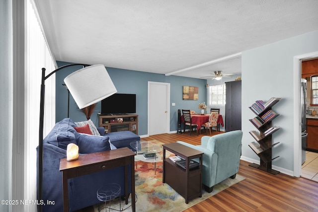 living room featuring ceiling fan, baseboards, and wood finished floors