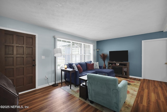 living room featuring a textured ceiling, baseboards, and wood finished floors