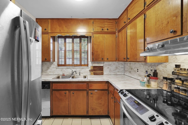 kitchen with a sink, decorative backsplash, light countertops, under cabinet range hood, and appliances with stainless steel finishes