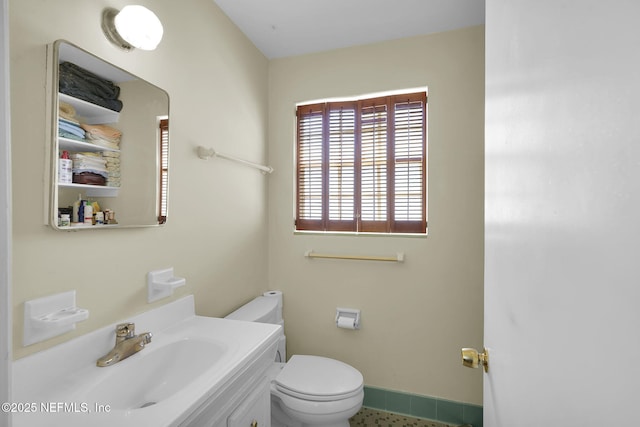 half bath featuring toilet, vanity, and baseboards