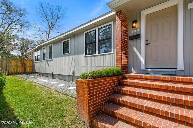 view of exterior entry featuring crawl space and fence