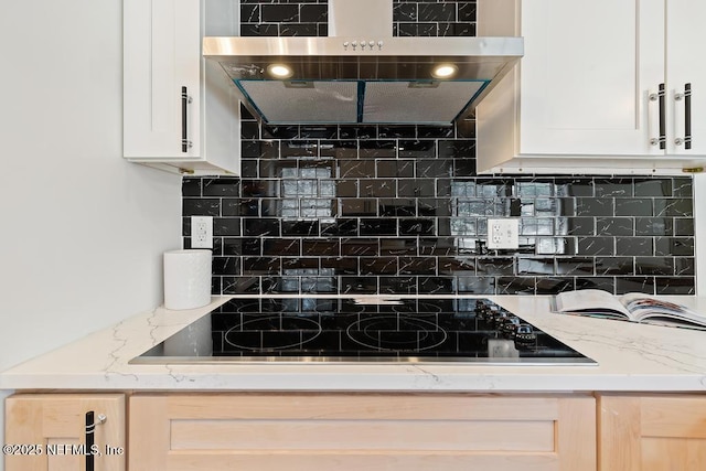 kitchen with white cabinetry, black electric stovetop, light stone countertops, and backsplash