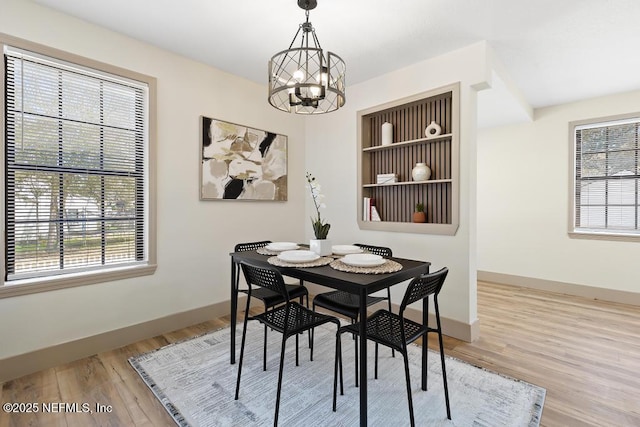 dining area with a chandelier, a healthy amount of sunlight, baseboards, and wood finished floors