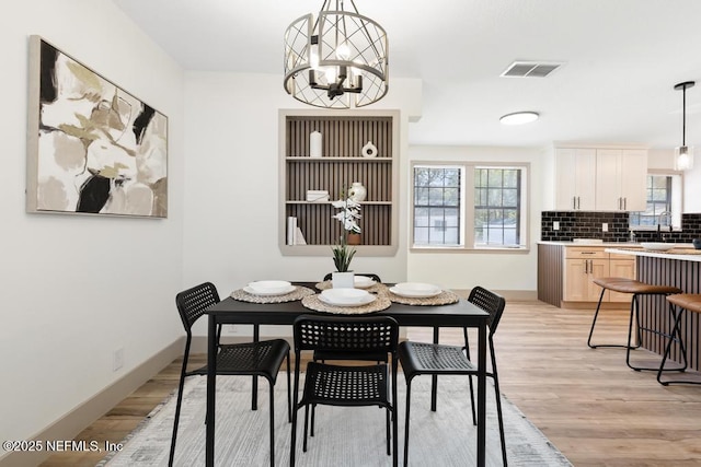 dining space featuring a chandelier, visible vents, light wood finished floors, and baseboards