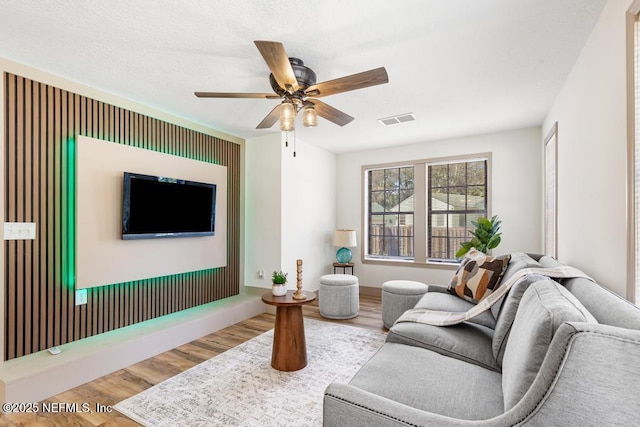 living area featuring visible vents, wood finished floors, and a ceiling fan