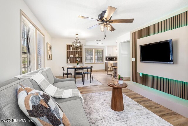 living room with light wood-style flooring and ceiling fan with notable chandelier