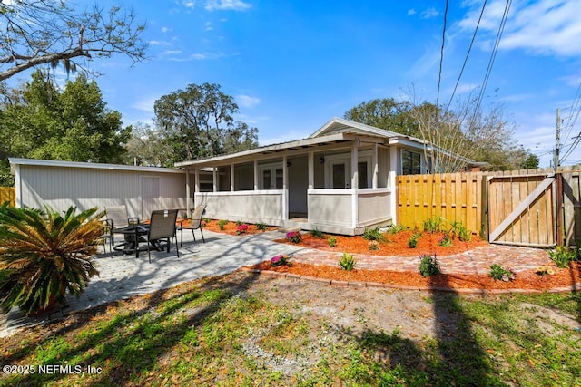 back of house with outdoor dining space, a gate, fence, a sunroom, and a patio area