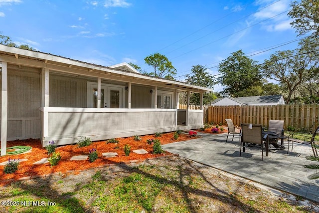 view of patio with outdoor dining space, fence, and french doors