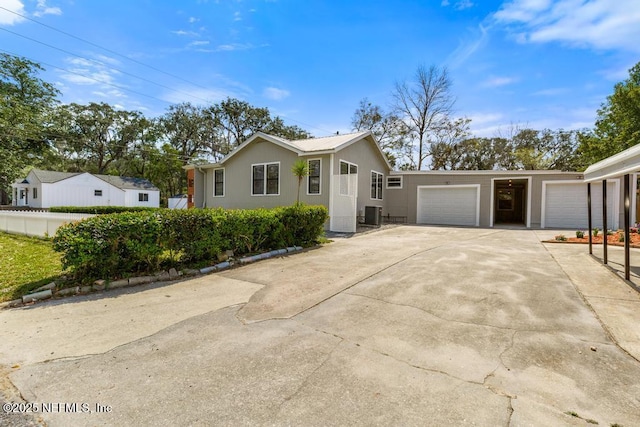 view of front of home with central air condition unit, concrete driveway, a garage, and fence