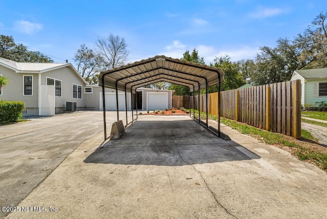 view of vehicle parking with a garage, a detached carport, concrete driveway, and fence