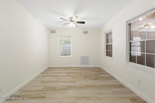 unfurnished room with ceiling fan, visible vents, and wood finished floors