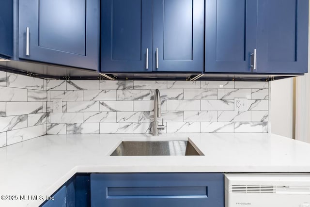 kitchen featuring light countertops, blue cabinets, and a sink