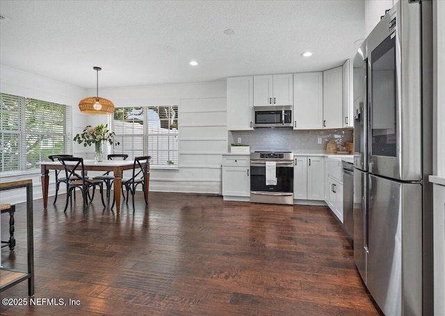 kitchen with dark wood finished floors, stainless steel appliances, light countertops, a textured ceiling, and backsplash