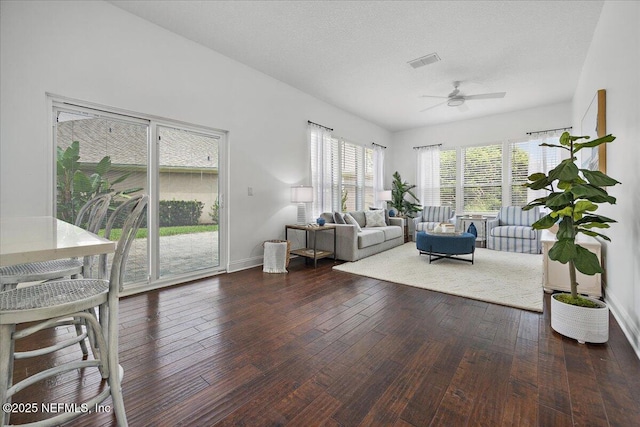 living area with visible vents, baseboards, hardwood / wood-style floors, a textured ceiling, and a ceiling fan