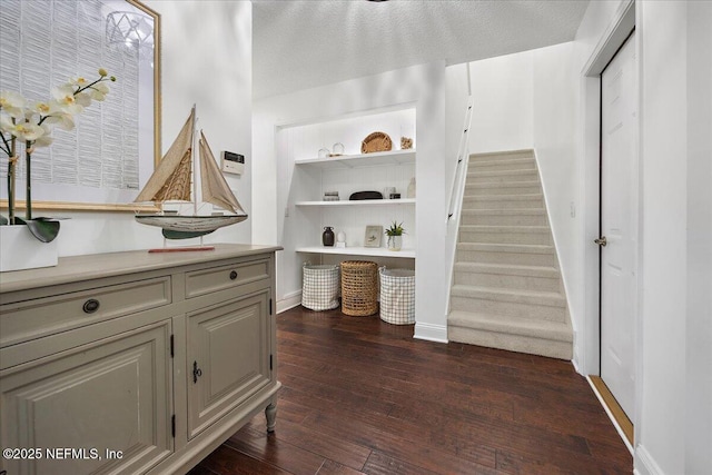 interior space featuring stairway, a textured ceiling, baseboards, and dark wood-style flooring