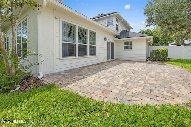 rear view of house with a patio area, stucco siding, and fence