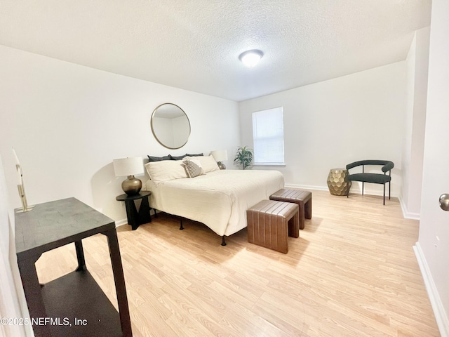 bedroom featuring baseboards, a textured ceiling, and light wood-style flooring