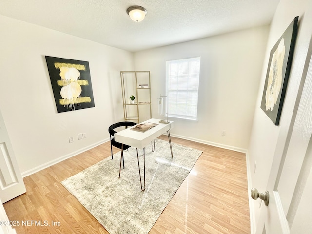 home office with baseboards, a textured ceiling, and light wood finished floors