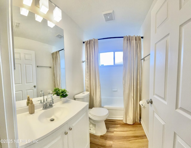 bathroom with visible vents, toilet, shower / tub combo, wood finished floors, and vanity