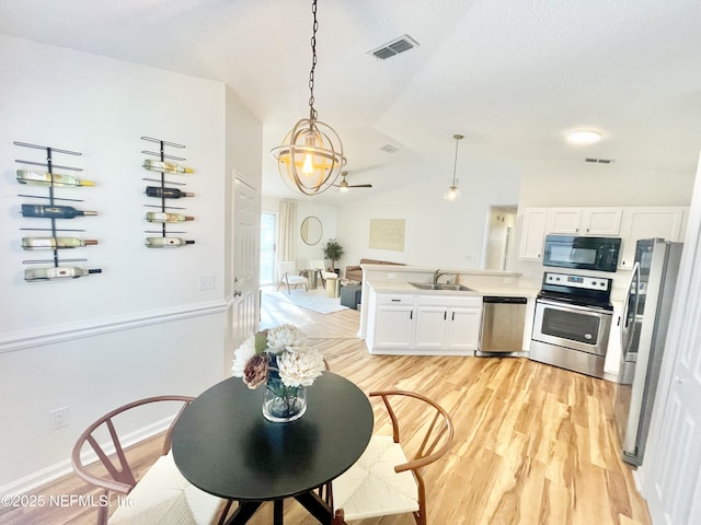 kitchen with stainless steel appliances, lofted ceiling, visible vents, and a peninsula