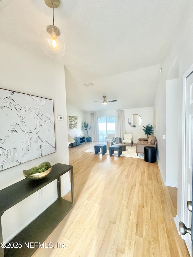 living area with vaulted ceiling, light wood-style flooring, and ceiling fan