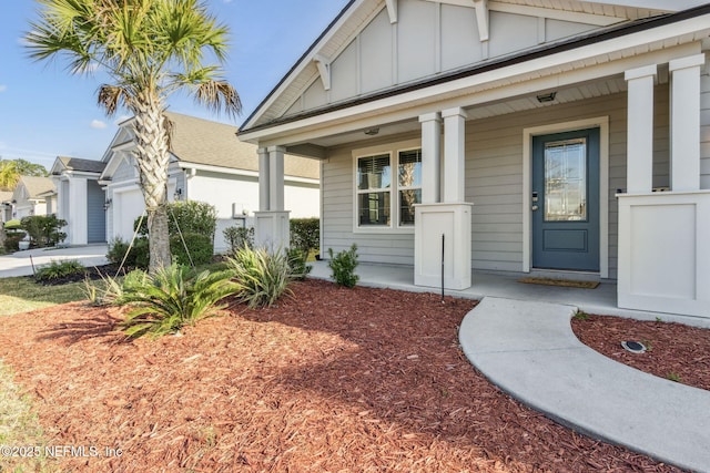 view of exterior entry featuring a porch, a garage, board and batten siding, and driveway