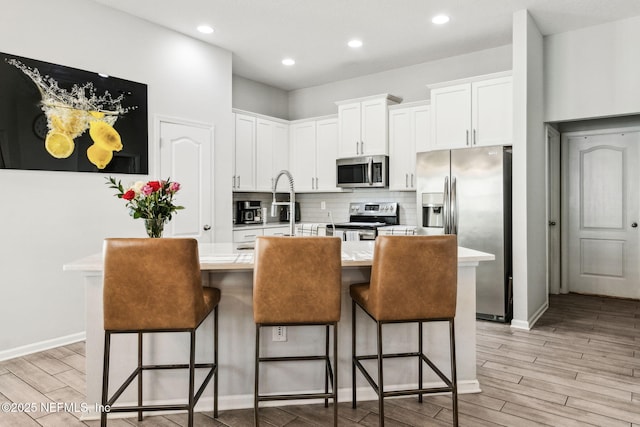 kitchen featuring stainless steel appliances, tasteful backsplash, light wood-style floors, and light countertops