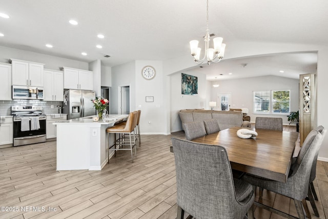 dining space featuring light wood-style flooring, recessed lighting, baseboards, lofted ceiling, and a chandelier