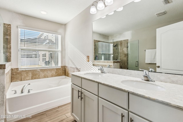 full bathroom with a sink, visible vents, a garden tub, and a shower stall