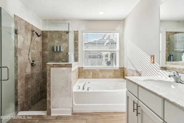 bathroom featuring a bath, a stall shower, vanity, and wood finish floors