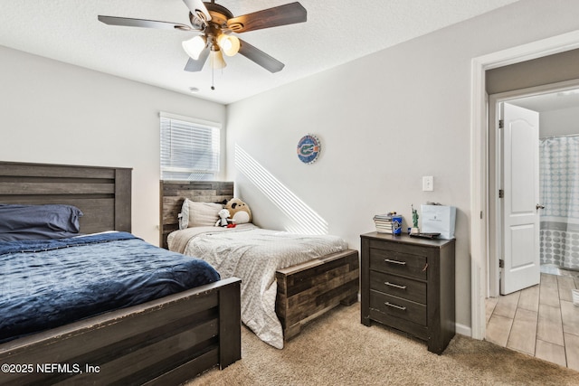 bedroom featuring light colored carpet, ceiling fan, and a textured ceiling