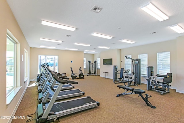 exercise room featuring baseboards, visible vents, and a textured ceiling