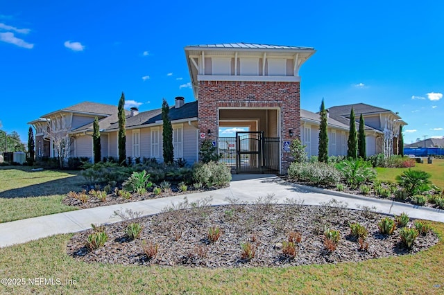 view of front of house with a front lawn, a gate, brick siding, and concrete driveway