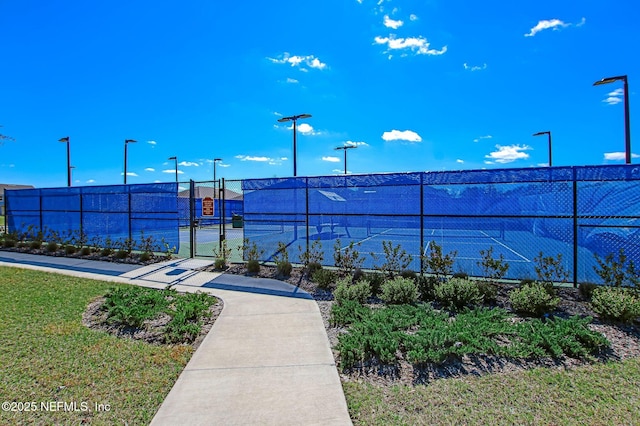 view of tennis court with a gate and fence