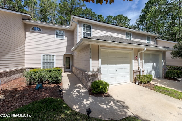 townhome / multi-family property featuring a garage, brick siding, and driveway