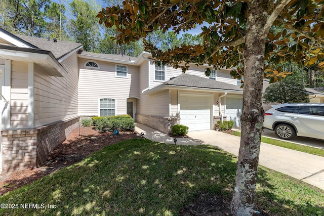 view of front of home with roof with shingles, concrete driveway, a front yard, a garage, and brick siding