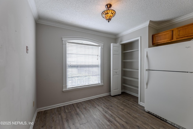 unfurnished dining area with dark wood-type flooring, ornamental molding, baseboards, and a textured ceiling