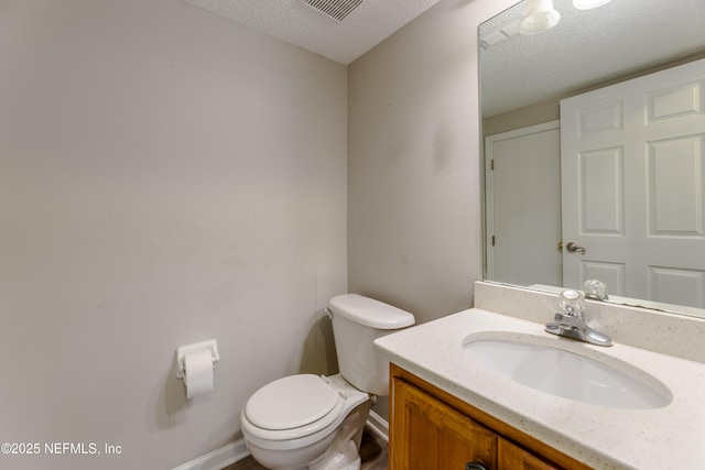 half bathroom featuring visible vents, toilet, vanity, and a textured ceiling