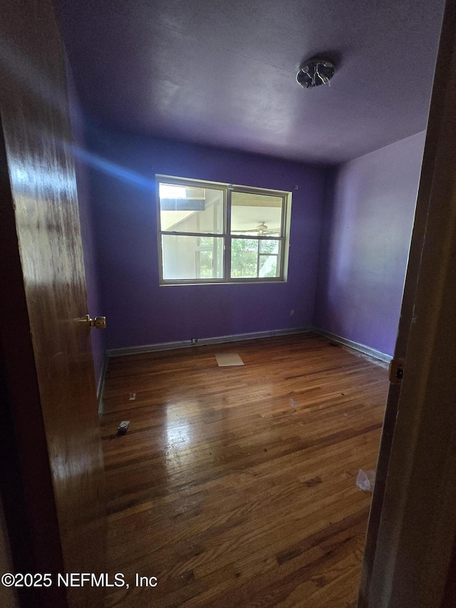 empty room featuring wood finished floors and baseboards