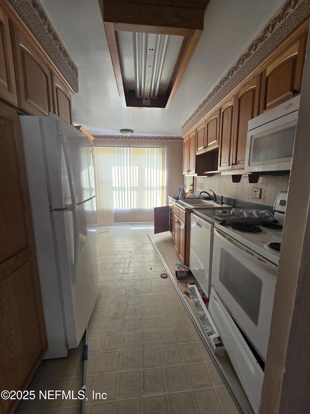 kitchen with tile patterned floors, white appliances, and a sink