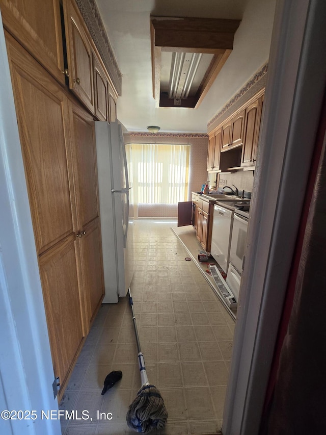 kitchen with brown cabinets, white appliances, and a sink