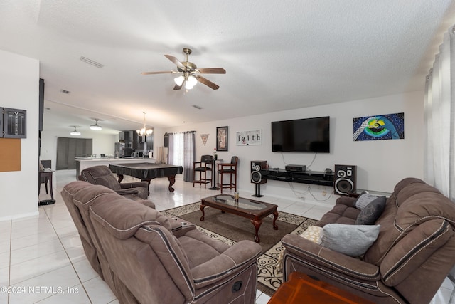 living area with light tile patterned floors, ceiling fan with notable chandelier, visible vents, and a textured ceiling