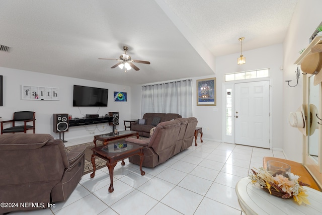 living area with light tile patterned floors, baseboards, visible vents, ceiling fan, and a textured ceiling