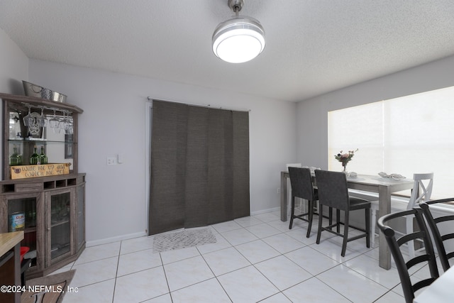 dining area with light tile patterned floors, baseboards, and a textured ceiling